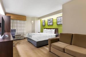 a hotel room with a bed and a couch at Sleep Inn at Greenville Convention Center in Greenville