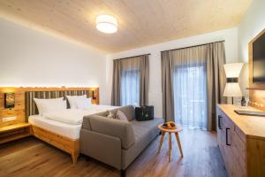 a bedroom with a bed and a couch and a bed at Hotel Trattlerhof in Bad Kleinkirchheim