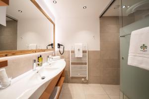 a bathroom with a sink and a shower at Hotel Trattlerhof in Bad Kleinkirchheim