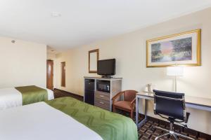 a hotel room with a bed and a desk and a tv at Quality Inn Lincoln Cornhusker in Lincoln
