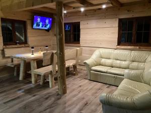 a living room with a table and a couch and a television at Ranczo Rico in Baryczka