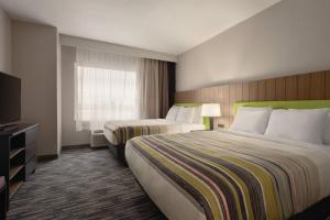 a hotel room with two beds and a television at Country Inn & Suites by Radisson, Champaign North, IL in Champaign