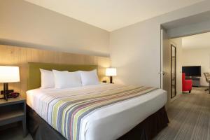 a hotel room with a large bed and a chair at Country Inn & Suites by Radisson, Champaign North, IL in Champaign