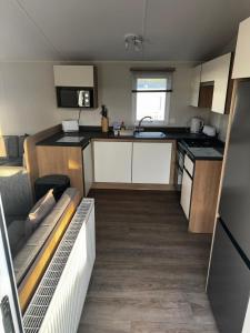 a small kitchen with white cabinets and a sink at Dixons Den Hot Tub in Swarland
