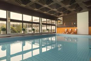 a swimming pool with a tub and chairs in it at Maritim Hotel Bellevue Kiel in Kiel