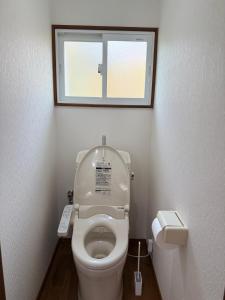 a small bathroom with a toilet with a window at 宿Oshikiri 04 in Shibushi +5 photos