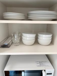 two white bowls and plates on a shelf at 宿Oshikiri 04 in Shibushi