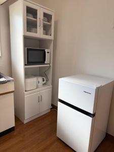 a kitchen with a white refrigerator and a microwave at 宿Oshikiri 04 in Shibushi