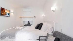 a white bedroom with a white bed and a fireplace at Nouvelle Studio in Epsom