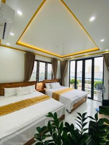 two beds in a room with large windows at Hotel 24h in Hai Phong