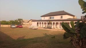 a large white house with cars parked in a yard at Crown Dove in Benin City +12 photos
