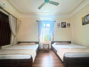 two beds in a room with a window at Ecohost Hai Trung in Háº£i Háº­u