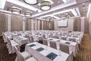 a room with white tables and chairs and a screen at Kantary 304 Hotel Prachinburi in Si Maha Phot