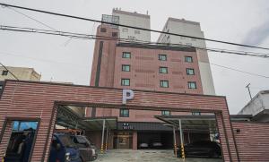 a large brick building with cars parked in front of it at Daejeon Comma Hotel in Daejeon