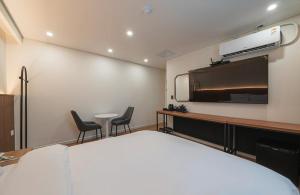 a hotel room with a bed and a flat screen tv at Daejeon Comma Hotel in Daejeon