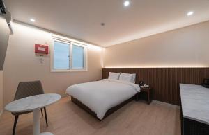 a bedroom with a bed and a table and a window at Daejeon Comma Hotel in Daejeon