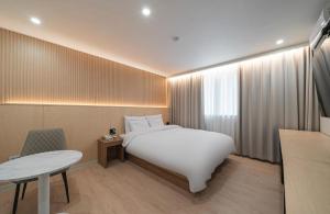 a hotel room with a white bed and a table at Daejeon Comma Hotel in Daejeon