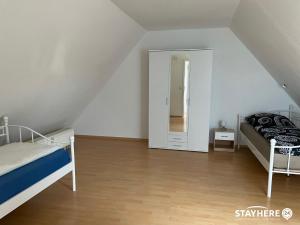 a attic bedroom with two beds and a mirror at StayHere24 Maisonette-Wohnung mit großem Garten in Leipzig