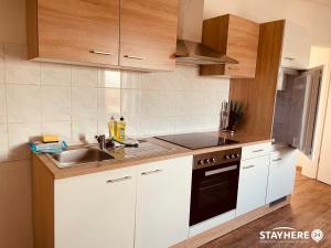 a kitchen with white cabinets and a sink at StayHere24 Maisonette-Wohnung mit großem Garten in Leipzig