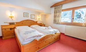 a bedroom with a wooden bed and a window at Hotel Wechselberger by Alpeffect Hotels in Saalbach-Hinterglemm