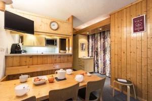 a wooden kitchen with a wooden table with chairs and a clock at Résidence Nova 1 - Appartement 2 pièces 6 personnes proche des pistes MAE-7984 in Arc 1800