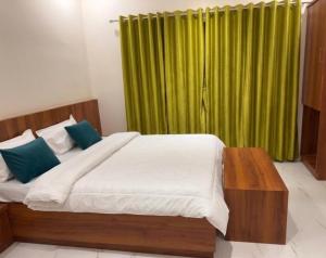 a bedroom with a large bed with a green curtain at Aanandi Resort in Shirdi