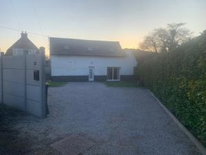 a white house with a driveway next to a fence at Chez Léon in Hasnon