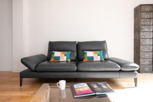 a black leather couch in a living room with a table at Beautiful House avec AC climatisation - terrasse privée - Côté pavé centre-ville Toulouse in Toulouse