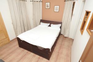 a bed with white sheets and pillows in a room at Spicened inn in Cochin