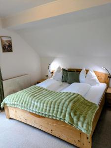 a large wooden bed with a green blanket on it at Bachbauer am Attersee in Weyregg
