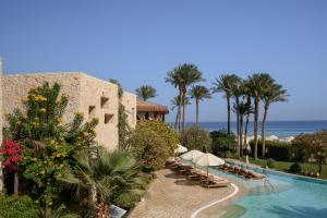 a resort with a swimming pool and palm trees and the ocean at The Makadi Spa Hotel - Couples Only 18 Years Plus in Hurghada