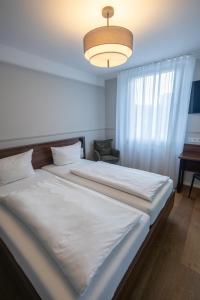 a bedroom with a large white bed and a lamp at Palazzo Hotel in Mannheim