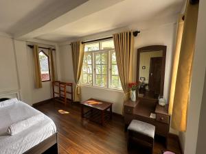a bedroom with a bed and a table and a mirror at The Woodside Manor in Nuwara Eliya