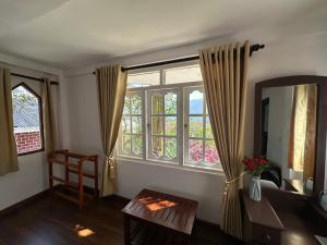 a living room with a window and a table and a mirror at The Woodside Manor in Nuwara Eliya