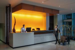 two men standing at a reception desk in a lobby at Chatrium Hotel Riverside Bangkok in Bangkok