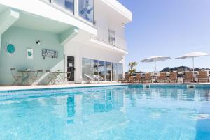 a swimming pool with chairs and umbrellas next to a building at Boutique Hotel Casa do Outeiro - Arts & Crafts in Batalha