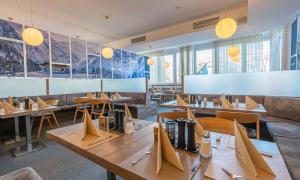 a restaurant with wooden tables and chairs and windows at Hotel Planai by Alpeffect Hotels in Schladming