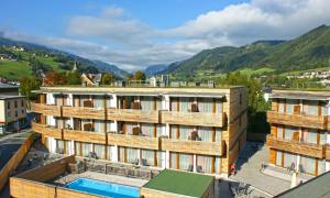 an apartment building with a swimming pool and mountains at Hotel Planai by Alpeffect Hotels in Schladming