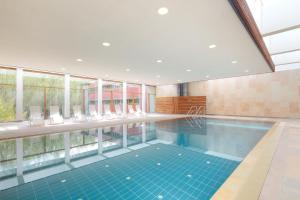 a swimming pool with chairs and a large window at Ostseehotel Dierhagen in Dierhagen