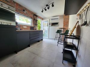 a kitchen with black cabinets and a brick wall at Studio Nessa with a private jacuzzi in Krk