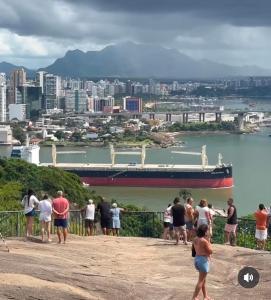 a group of people looking at a ship in the water at Ambiente familhiar in Guarapari