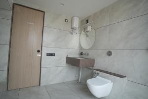 a bathroom with a toilet and a sink and a mirror at Mahadev Hotel in Botād