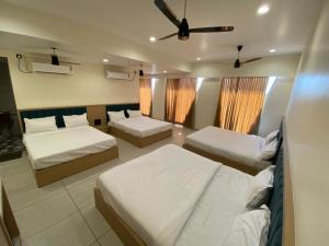 a bedroom with three beds and a ceiling fan at Mahadev Hotel in Botād