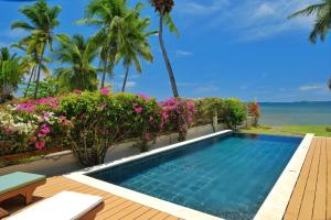 a swimming pool in a villa with flowers and the ocean at Villa Mora Mora in Nosy Be