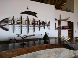 a bar with a counter with bottles and a fish on the wall at Villa Mora Mora in Nosy Be