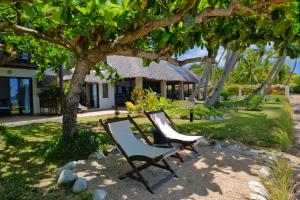 two chairs under a tree in front of a house at Villa Mora Mora in Nosy Be