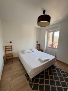 a bedroom with a bed and a chair and a window at L' Annexe Barneville Bourg in Barneville-Carteret