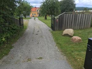 a gravel road with a fence and two rocks at Lilla Skottek in Ulricehamn