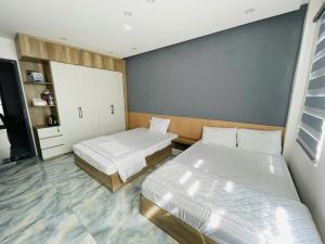 a bedroom with two beds and a cabinet at Hotel Trâm Anh 1 in Nhơn Trạch