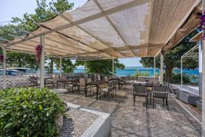 a patio with tables and chairs under a wooden umbrella at Martin's B&B in Dramalj